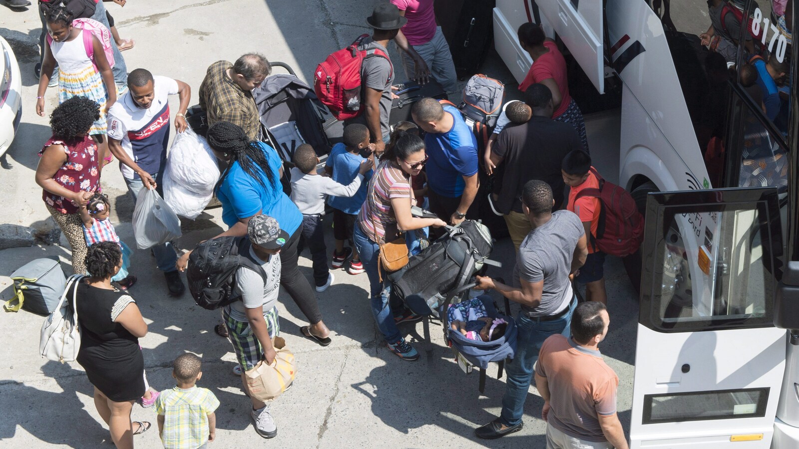 Des migrants arrivent au stade olympique de Montréal, où ils seront logés temporairement.
