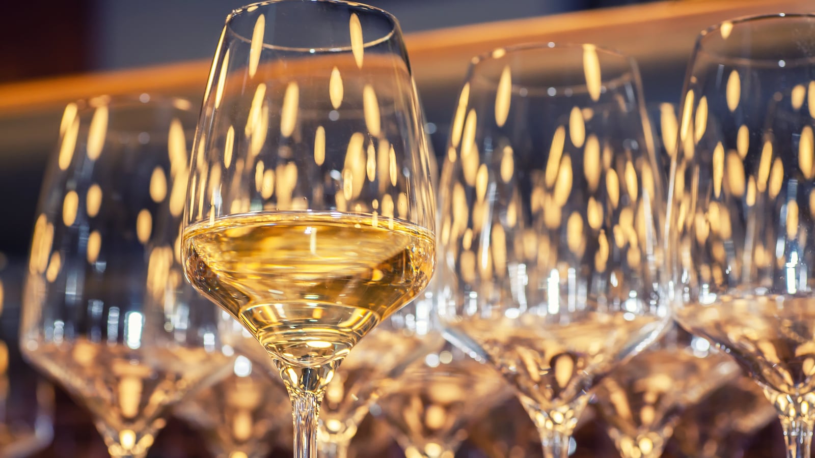 Un verre de vin blanc est au premier plan avec plusieurs verres derrière.