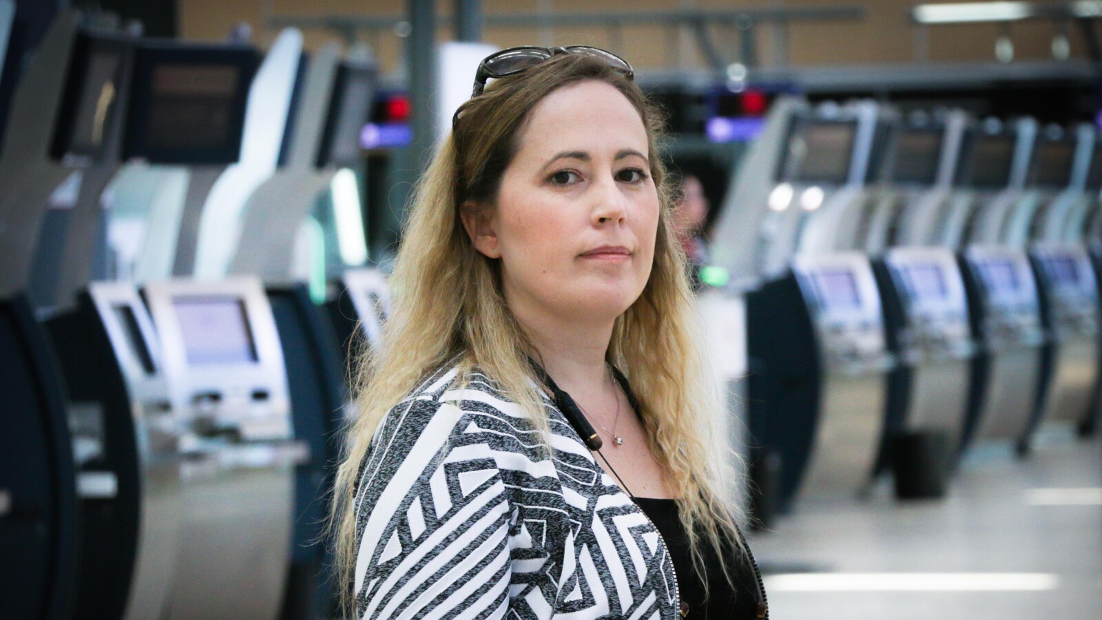 Jill Knapp se tient debout devant des bornes d'enregistrement à l'aéroport de Vancouver.