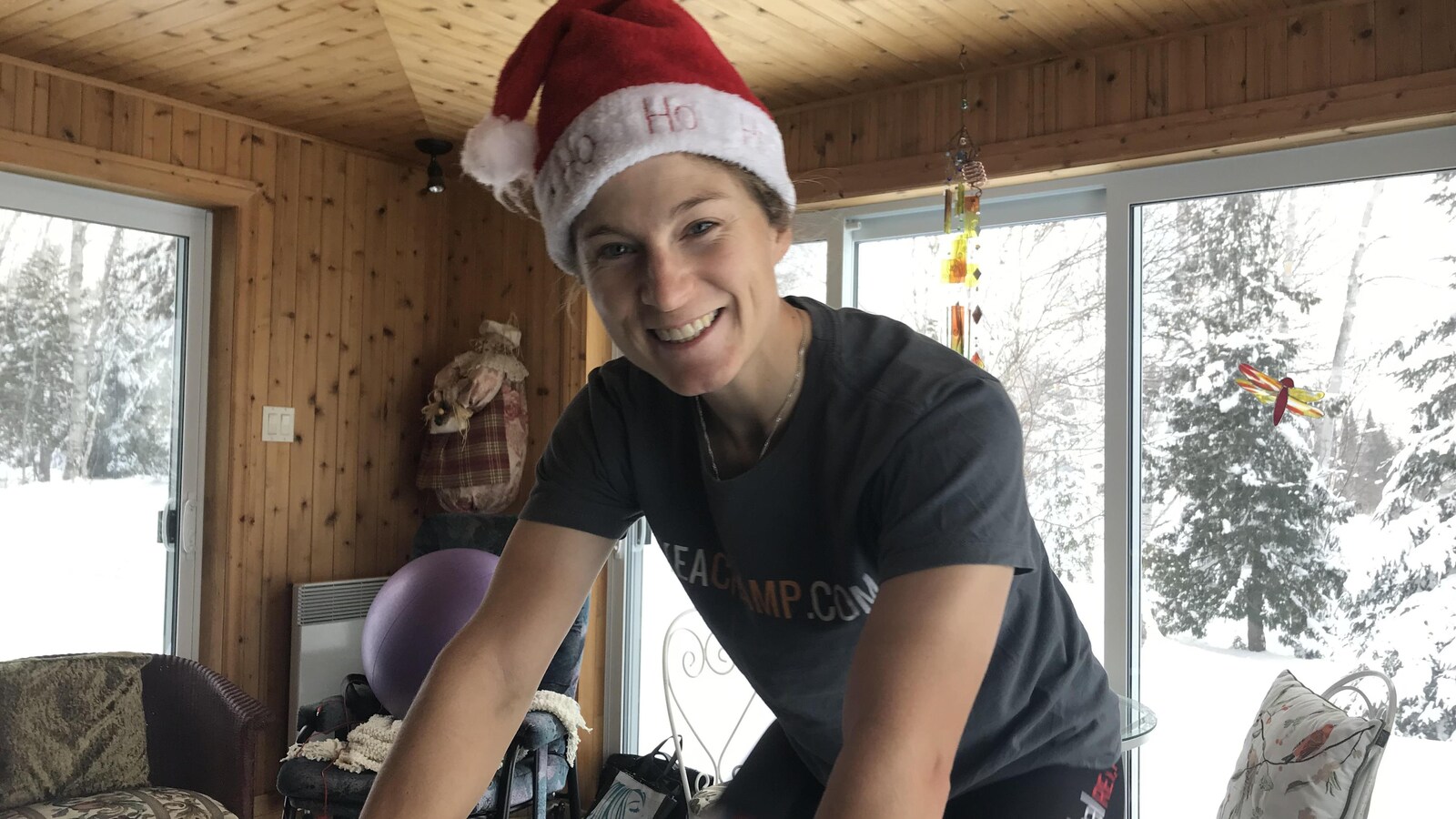 La cycliste Cindy Montambault est souriante avec une tuque de Noël sur un vélo stationnaire.