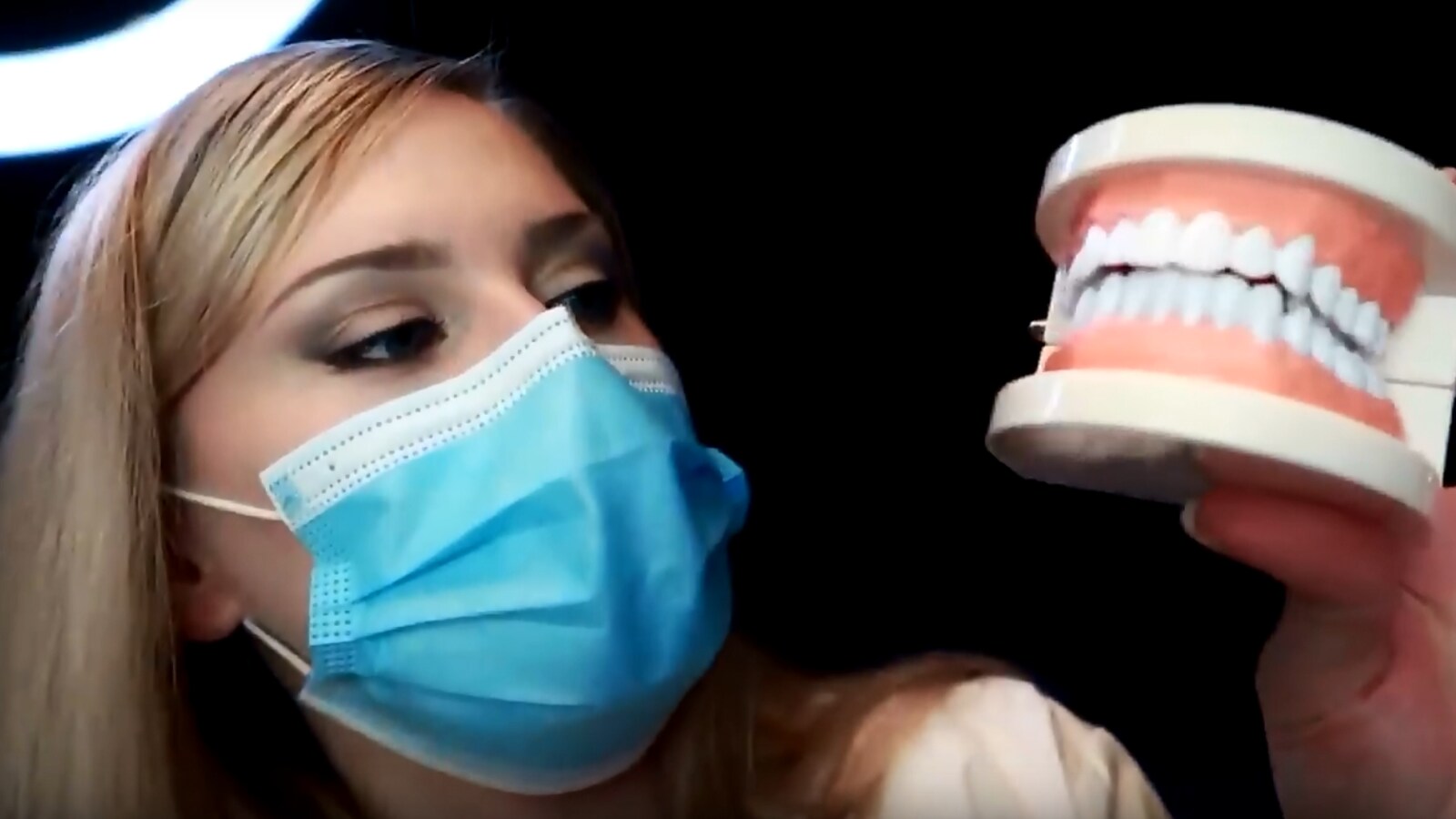 La jeune femme tient en main un dentier.