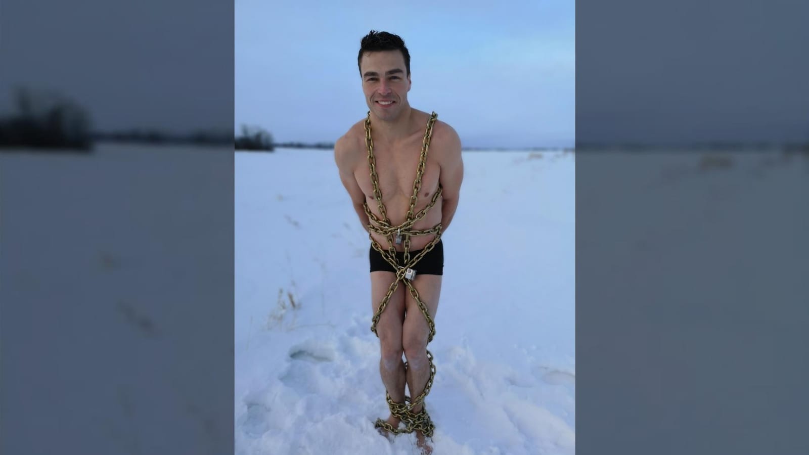 Roger Boucher en maillot de bain, debout et enchaîné, dans la neige.