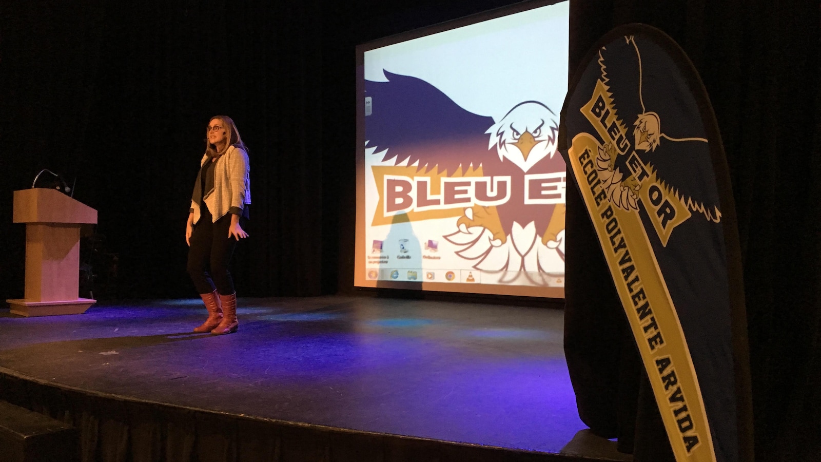Sylvie Fréchette est sur scène devant un écran affichant le logo du Bleu et Or.