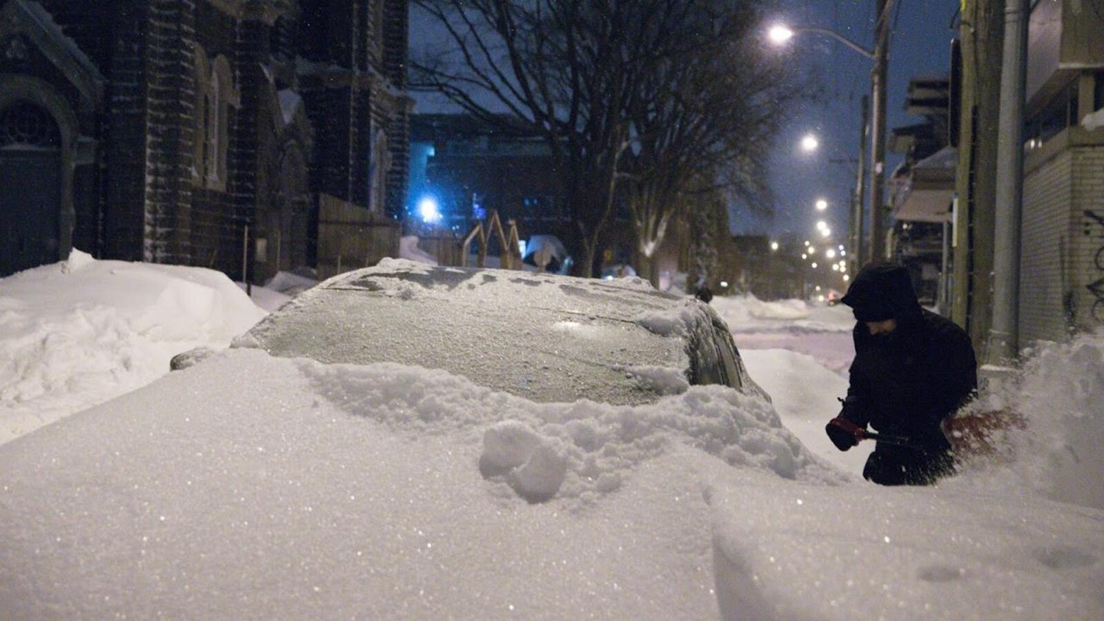 Un homme déneigeant sa voiture près de l'église St-Charles