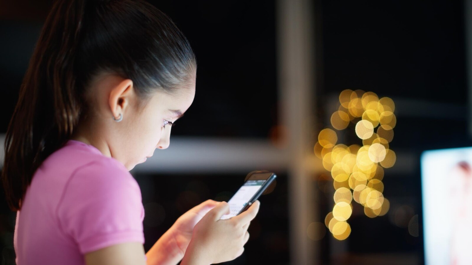 Une jeune fille regarde son téléphone cellulaire avec une attention soutenue.