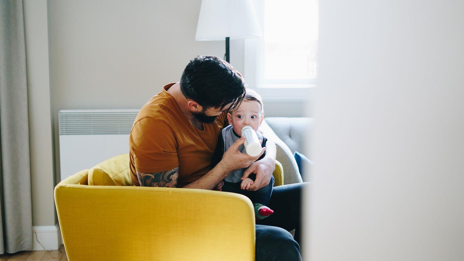 Un père de famille nourrit son bébé au biberon.