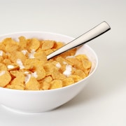Un bol de céréales blanc avec du lait et une cuillère. 