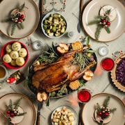 Vue de dessus du dîner de Noël traditionnel servi sur table. Menu du réveillon de Noël de canard rôti, boulettes et chou rouge avec du vin rouge sur une table à manger décorée.