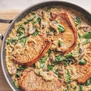 Une casserole remplie de côtelettes de porc et d'orzo à la crème aux champignons.