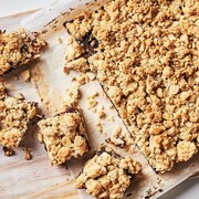 Une plaque de carrés au dattes à l'orange et aux amandes sur une planche à découper.