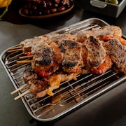 Des brochettes de porc et de crevettes sur une grille sortant du four.