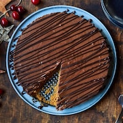 Une tarte dans une assiette avec une pointe manquante. Elle est entourée de décorations de Noël. 