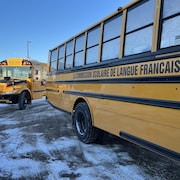 Deux autobus scolaires arrivent à une école.