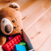 Boîte de jouets avec des blocs et un ourson en peluche.