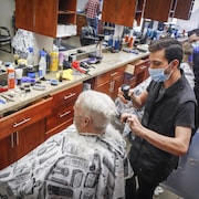 Des coiffeurs coiffent des clients avec un masque.