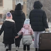 Une famille portant des vêtements d'hiver, dont les membres sont vus de dos.