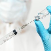 Un médecin tient un flacon de vaccin et une seringue pour l'injection.