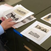 Raymond Frogner tient des photos d'archives dans ses mains.