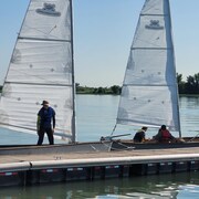 Des jeunes sont assis dans un voilier accosté à un quai.