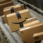 Des boîtes de carton sur un tapis roulant portent le logo d'Amazon.