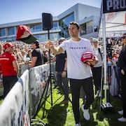 Il lance des casquettes rouges à la foule.