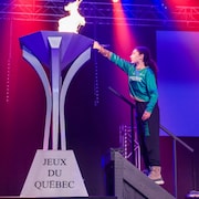 Une jeune fille allume la flamme des Jeux du Québec.