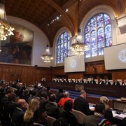 Des personnes sont assises &agrave; l'int&eacute;rieur de la Cour internationale de justice (CIJ) le jour du proc&egrave;s pour entendre une plainte de l'Afrique du Sud, qui accuse Isra&euml;l de g&eacute;nocide.