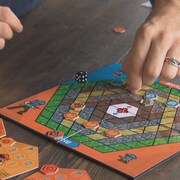 Une planche de jeu colorée disposée sur une table et des mains qui y jouent. 