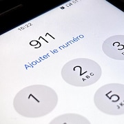 Une personne compose le 9 1 1 sur son cellulaire.