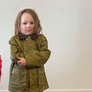 Un jeune gar&ccedil;on habill&eacute; en vert croise les mains sur sa poitrine.