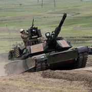 Un soldat sur un tank qui monte une côte.