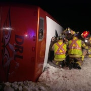 Du personnel des services d'urgence ouvre une sortie de secours après l'accident en février 2015, tout près de Grand Falls - Windsor, de l'autobus qui transportait des patineuses.
