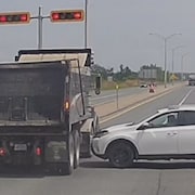Une voiture est immobilisée à côté d'un camion.