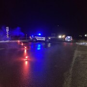 Une voiture de police bloque une voie où il y a des fusées éclairantes sur la chaussée.
