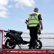 Un policier devant une mobylette. 