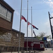 Trois drapeaux sont en berne devant un édifice.
