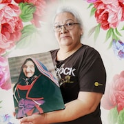 Une femme présente le portrait d'une autre femme, sa grand-mère.
