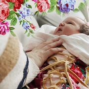 Un bébé avec la main de sa mère, avec un graphisme fleuri.