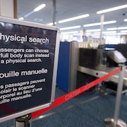 Un écriteau en français et en anglais qui explique aux passagers d'un aéroport qu'ils peuvent choisir un scanner corporel au lieu d'une fouille manuelle.