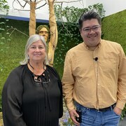 Une femme et un homme pose devant un mur fait de plantes.