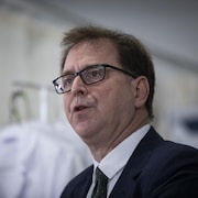 Le ministre de la Santé, Adrian Dix, debout lors d'un discours 