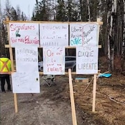 Des affiches pour améliorer l'éducation des enfants sont posées sur un cadre de bois à l'entrée de Kitcisakik.