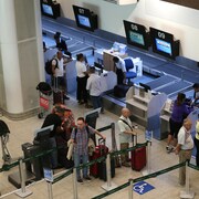 Des passagers font la file pour enregistrer leurs bagages à un comptoir d'une compagnie aérienne à l'aéroport de Rio de Janeiro.