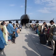 Des arrimeurs et des pilotes de l'armée de l'air américaine supervisent l’embarquement des passagers à bord d'un C-17 Globemaster III.