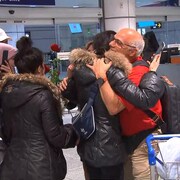 Des gens se serrent dans leurs bras à l'aéroport.