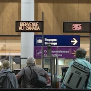 Des passagers avancent vers l’accueil aux Douanes canadiennes à l’aéroport international Trudeau à Montréal pour les formalités d'entrée au pays.  