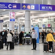 Des voyageurs aux comptoirs d'un aéroport.