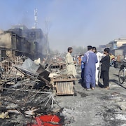 Des gens parlent près de bâtiments détruits.