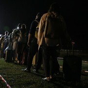 Des Afghans font la file, la nuit, pour entrer dans un véhicule de transport.
