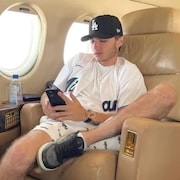 Aiden Pleterski consulte son téléphone dans un jet privé.